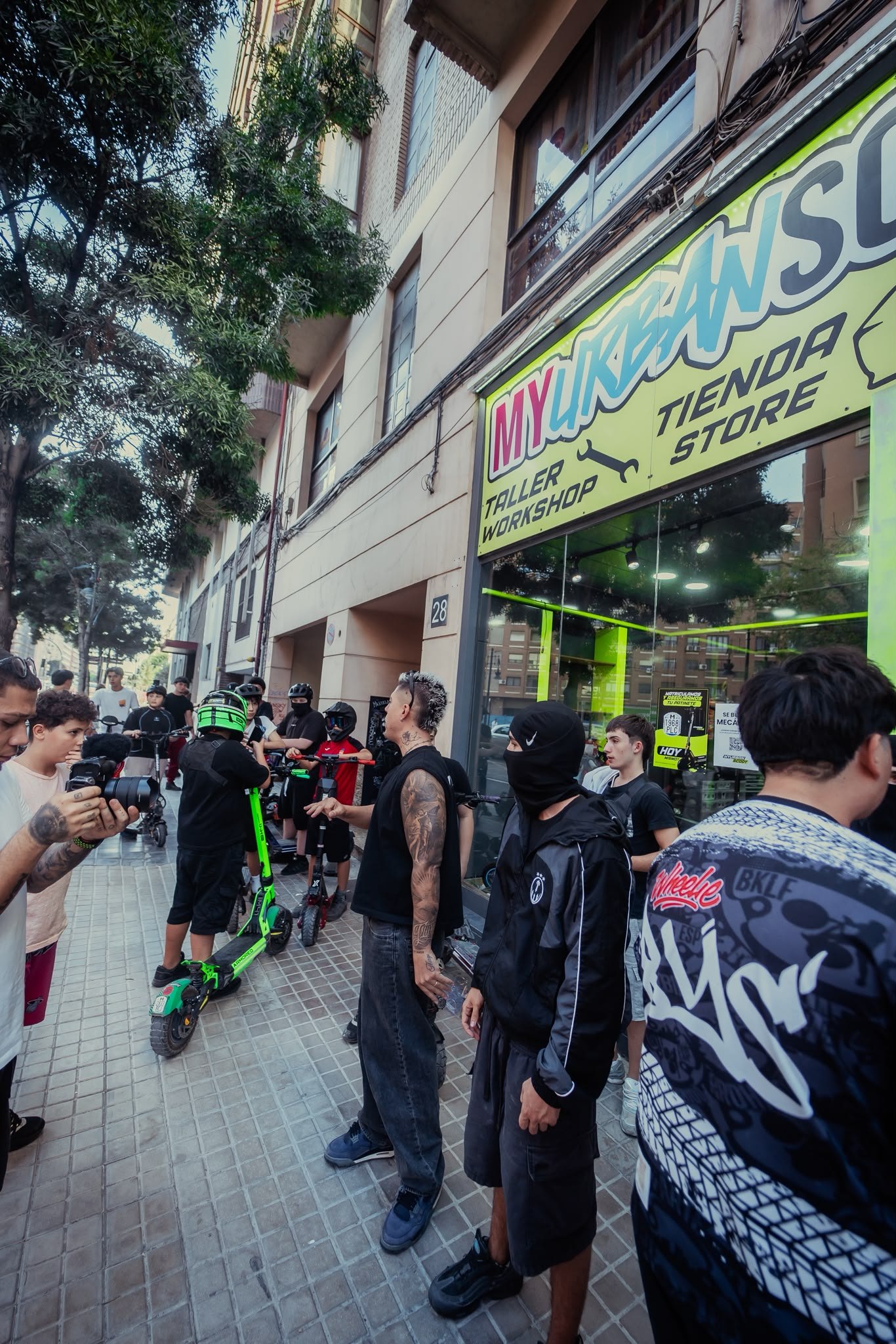 Fachada de la tienda y taller MyUrbanScoot en Valencia con riders y patinetes en la acera